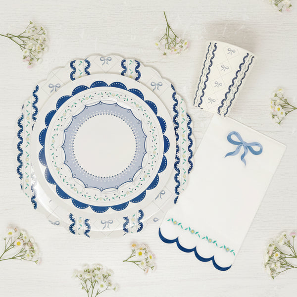 Floral and bow detail on blue scalloped paper napkins for baby showers and baptisms