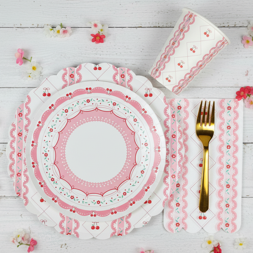 Simple birthday party ideas — Coquette Cherry themed party supplies box with pink cherry-patterned plates, cups, napkins, and gold cutlery