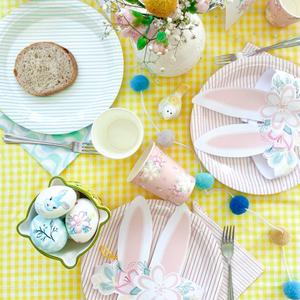 Easter-themed table setting with pastel colors on a yellow checkered tablecloth.