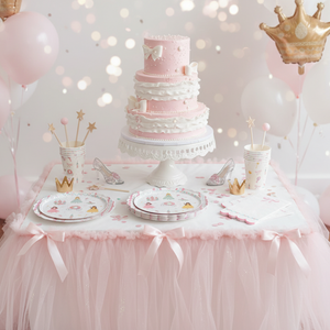 Pink and white cake on a table with balloons and decorative elements