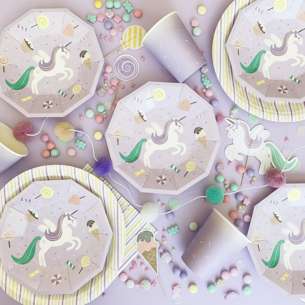 Unicorn-themed party supplies including plates and cups on a light background
